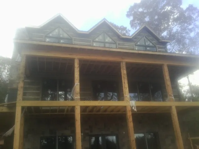Dormers and porch framing on a large log home under construction — Roof Coating work by our crew in Luttrell