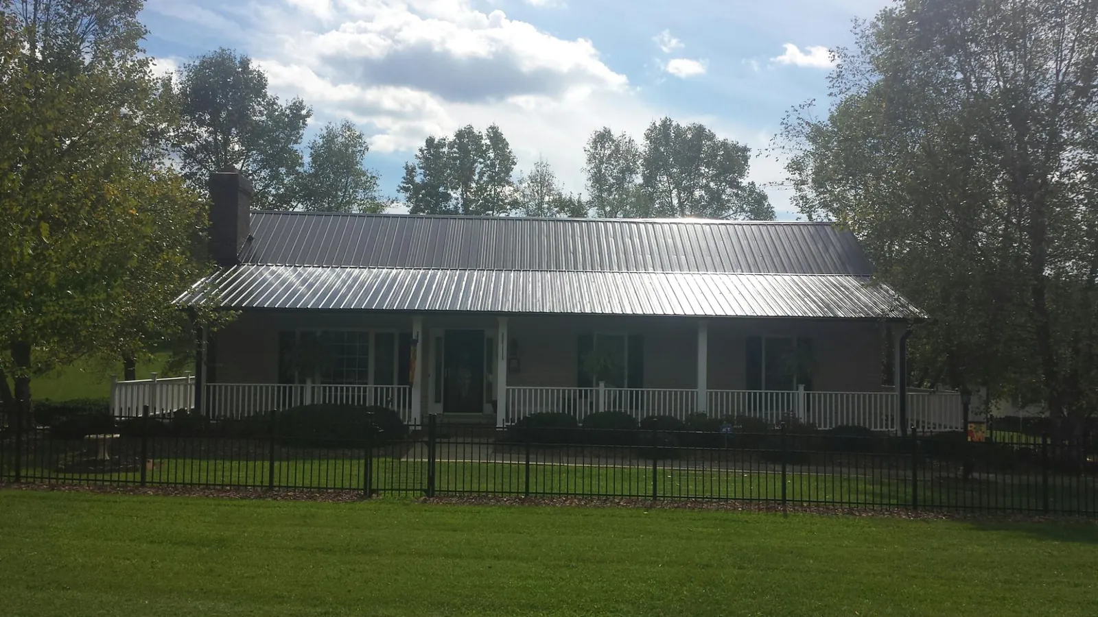Gray metal roof on a brick ranch with a full width front porch — Gutter Guard Installation work by our crew in Luttrell