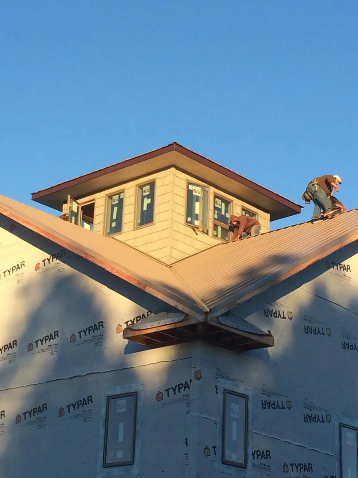 Roofers working around a rooftop cupola on a new metal roof at sunset — Roof Waterproofing in Luttrell by Roofing Brothers